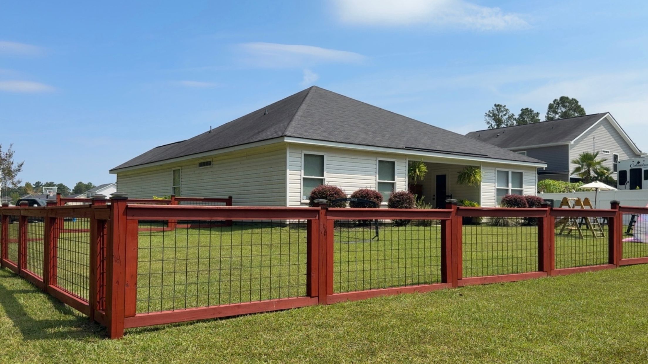 Custom red-stained fence with wire panels around a residential yard